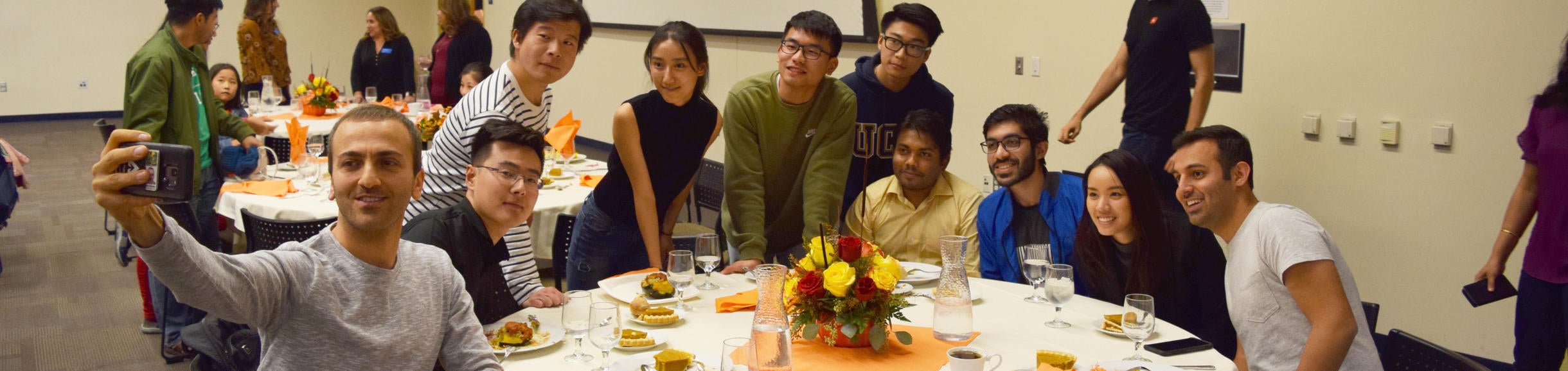 Group of students and scholars taking selfie at thanksgiving table