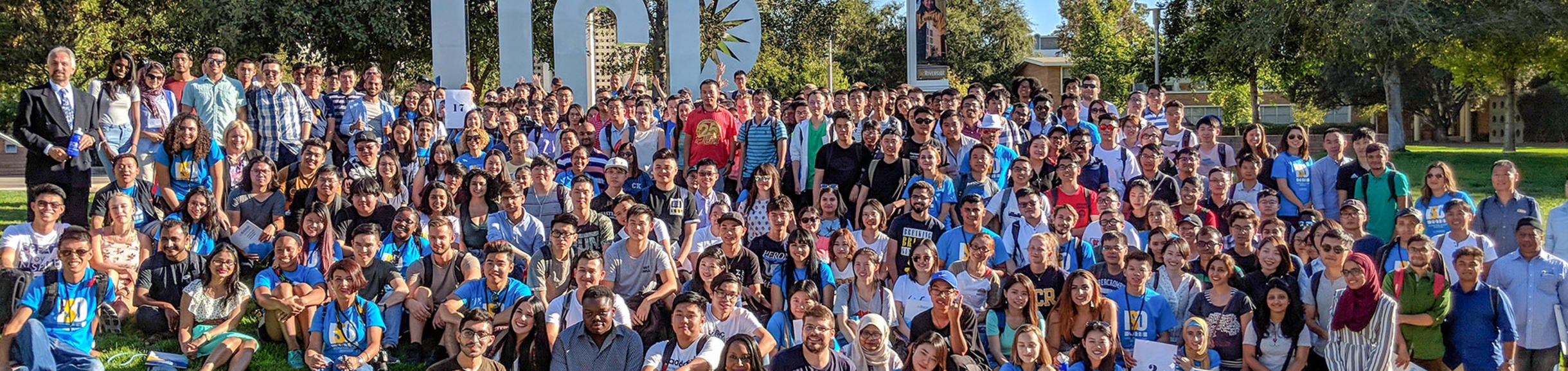 Large group of international students posing in front of UCR letters